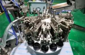 Detail view of aluminum tube crimping and folding station on a paint packaging production line