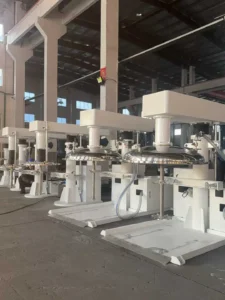 A row of Z-MIXER high-speed dispersers with hydraulic lifting mechanisms and stainless steel vacuum covers, designed for epoxy resin pre-mixing and dispersion.